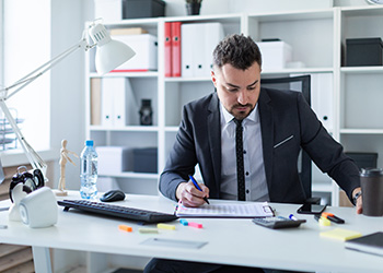 Businessman at His Desk Writing on Clipboard